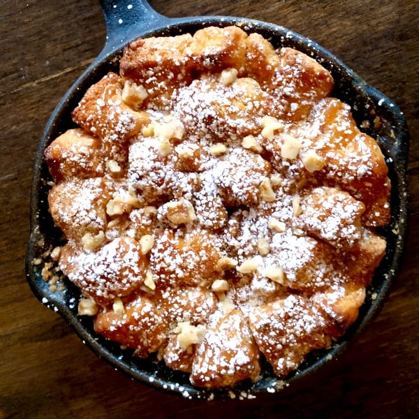 Kanela Breakfast Club's monkey bread, dusted with powdered sugar and nuts, in a cast iron skillet.